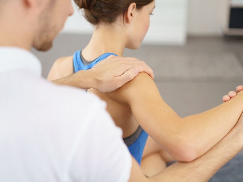 Physical Therapist Massaging the Injured Arm and Shoulder of a Young Woman